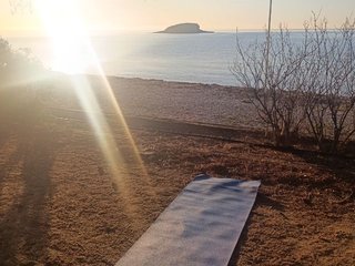 Sunrise over the Guadalest reservoir with a person meditating on the shore